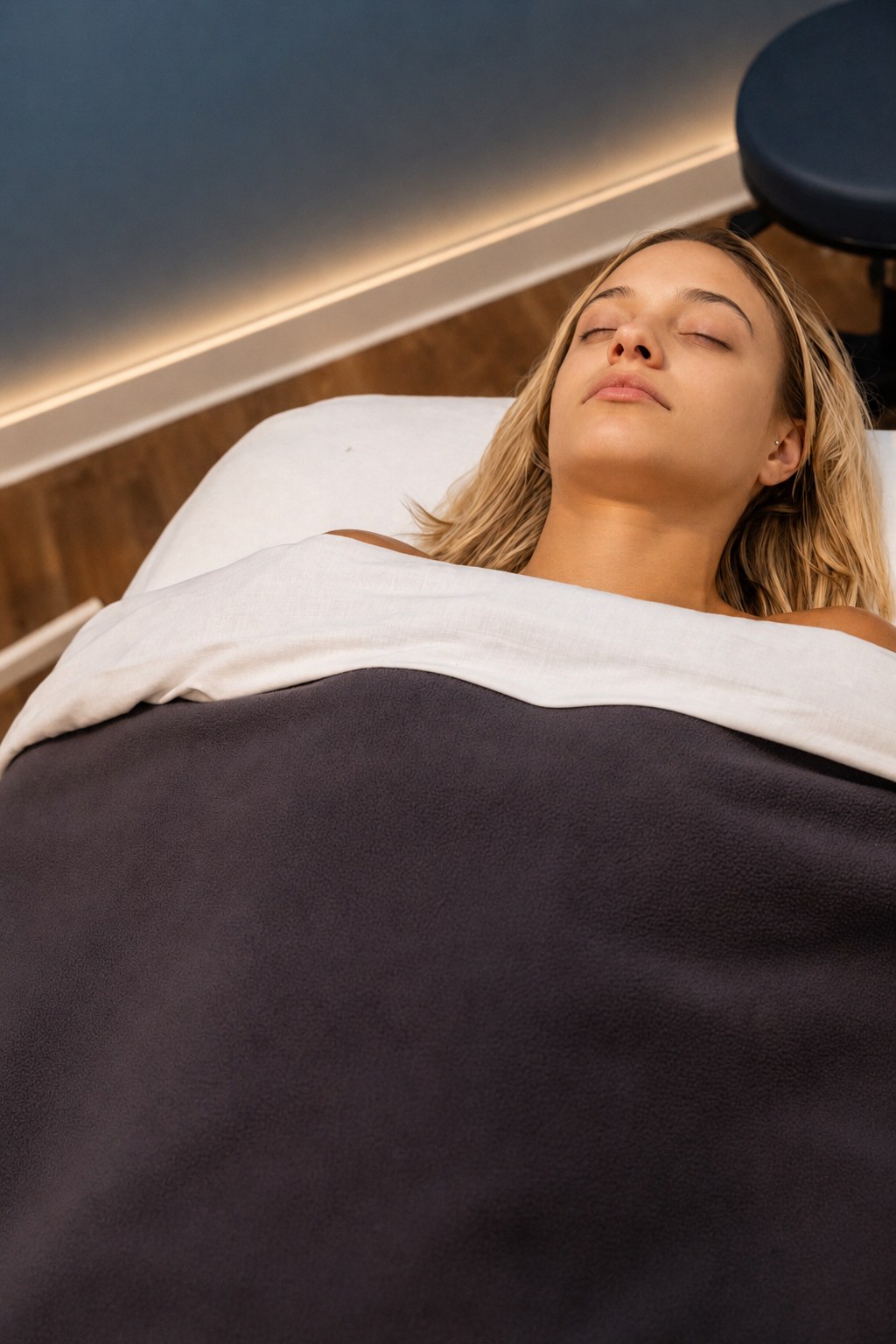 Client resting peacefully under a soft blanket after a prenatal massage