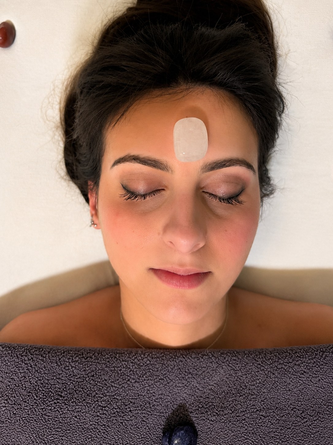 A crystal resting at the brow during a chakra balancing session
