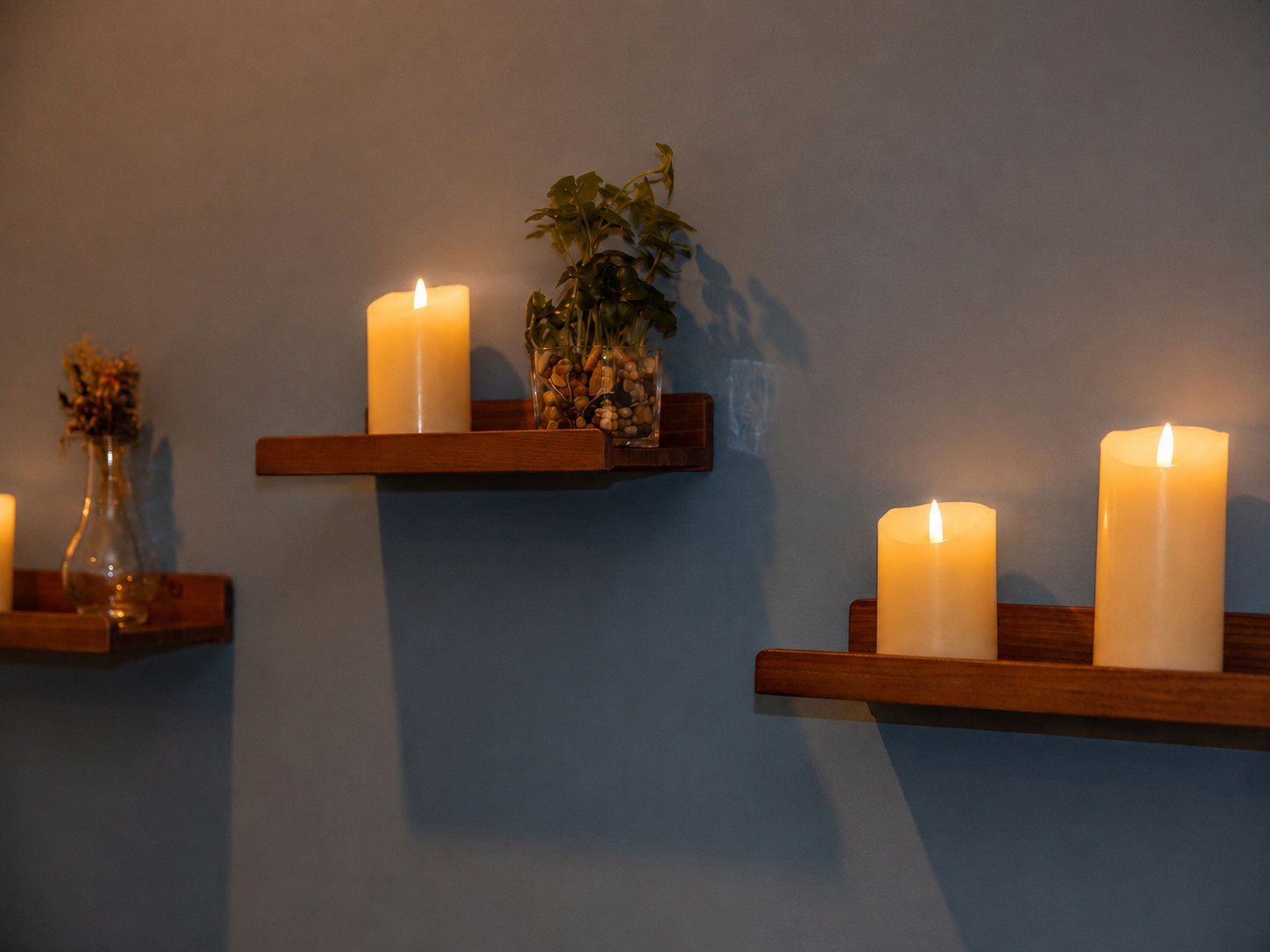 Pillar candles glowing on floating shelves against a deep blue wall at the Portsmouth studio